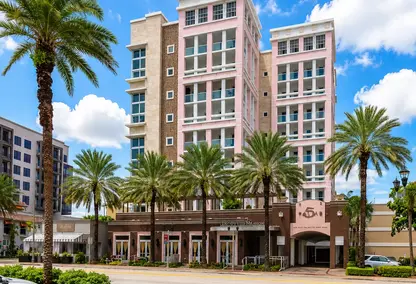 5 Palms Condo in downtown Boca Raton with palm-lined street, pink luxury building, and South Florida real estate appeal.
