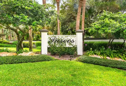 Paseos gated community entrance in Boca Raton, South Florida with tropical landscaping, palm trees, and manicured green space.