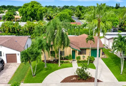 Sandalfoot Estates home in West Boca Raton, South Florida featuring tropical landscaping, palm trees, driveway, and suburban curb appeal.
