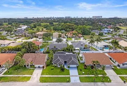 Aerial view of single-family homes in Hidden Valley Boca Raton with golf course and city skyline in the distance.