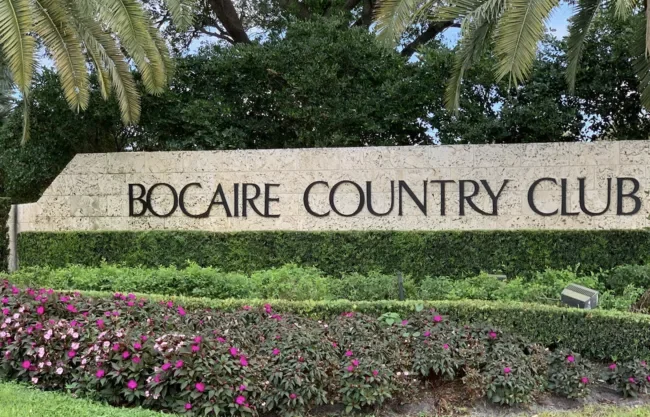 Entrance sign for Bocaire in Boca Raton, surrounded by flowers, greenery, and tropical landscaping.