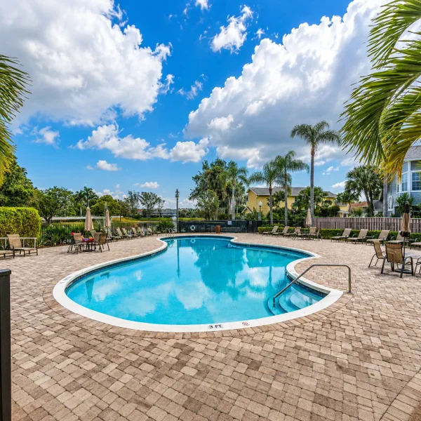 Carriage Houses in Fairfield at Boca, Boca Raton real estate, neighborhood amenities: pool area with palm trees, paved patio, lounge seating.