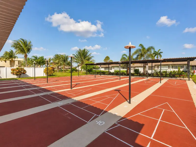 Crosley neighborhood shuffleboard courts in West Palm Beach with palm trees, blue sky, and active adult community living.