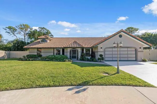 Single-story home in Deerpark Estates with tile roof, two-car garage, manicured lawn, and circular driveway.