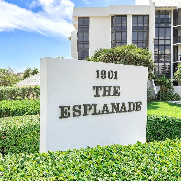 Esplanade Condominiums in Boca Raton, FL with entrance sign, tropical landscaping, and near-beach condo living.