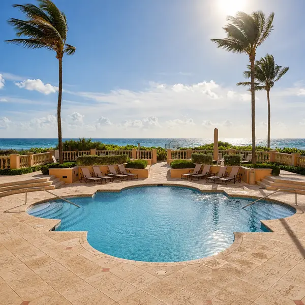 Excelsior Boca Raton oceanfront pool with palm trees, lounge seating, and luxury beachfront amenities.