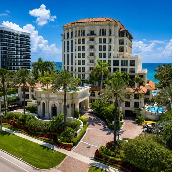 Excelsior Boca Raton luxury beachfront condo exterior with resort-style entrance, palms, and Atlantic Ocean backdrop.