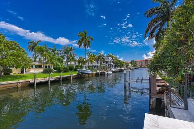 Waterfront view of canal homes in Harbour East, Boca Raton with private docks, boats, and tropical palm trees.