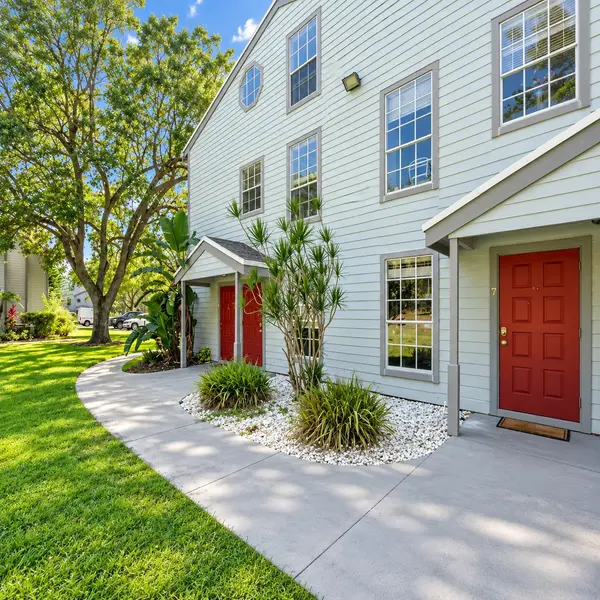 Heatherwood Boca Raton condo building with red doors, garden walkway, mature trees, and tropical landscaping.