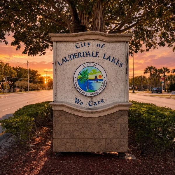 Lauderdale Lakes City sign in South FL with sunset sky, tropical landscaping, and luxury real estate lifestyle appeal.