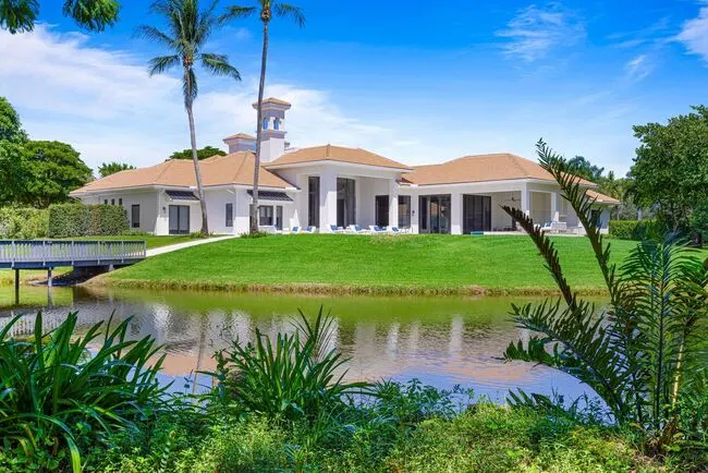 Modern luxury waterfront estate in Le Lac, Boca Raton featuring tropical landscaping, private lake views, and open-air design.