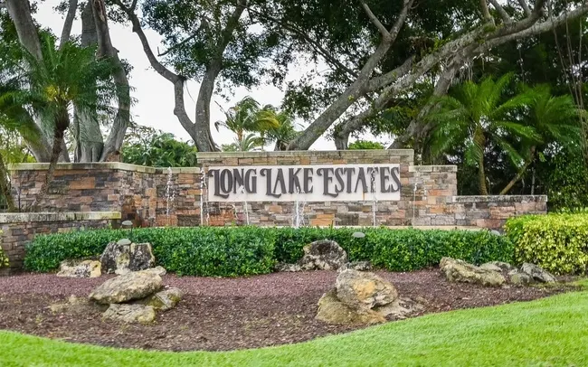 Long Lake Estates entrance sign in Boca Raton, FL, featuring modern stone design, tropical landscaping, and community branding.