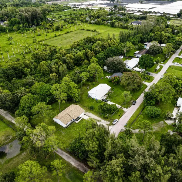 Loxahatchee Groves aerial view featuring homes on large lots, lush greenery, open land, and rural South Florida real estate.
