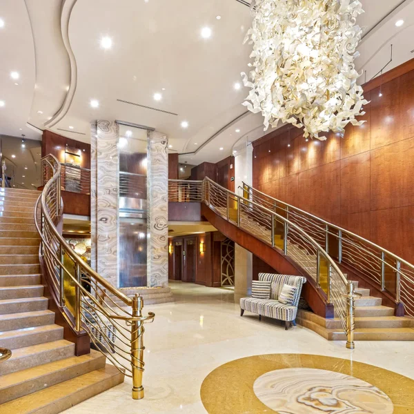 Luxuria condos Boca Raton luxury real estate lobby with grand staircase, chandelier, marble floors, and upscale coastal condo design.