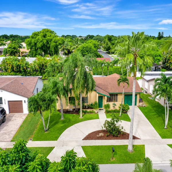 Sandalfoot Estates home in West Boca Raton, South Florida featuring tropical landscaping, palm trees, driveway, and suburban curb appeal.
