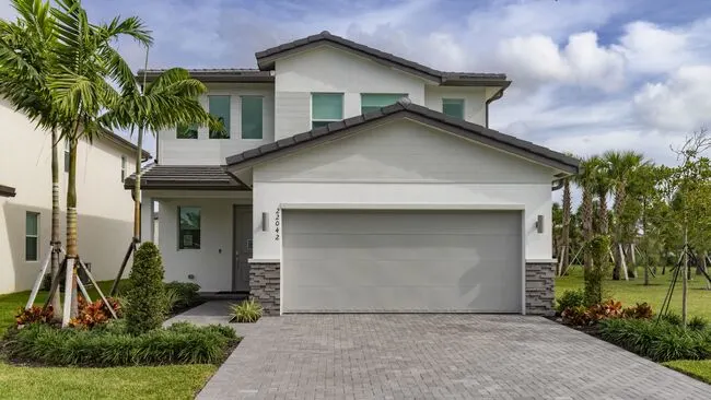 Front view of a modern single-family rental home at Nuvo Boca in Boca Raton, featuring a two-car garage and landscaping