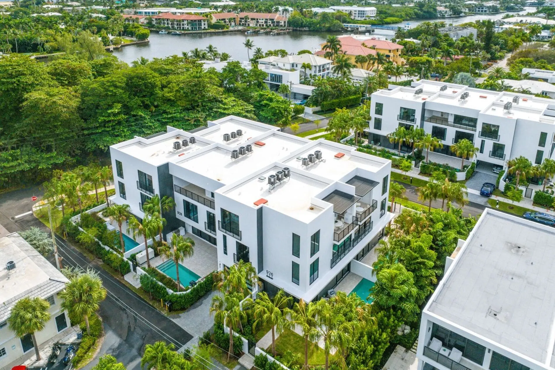 Aerial view of modern townhomes homes at the Palm Trail community in Delray Beach with green landscaping and intercostal in the backdrop.