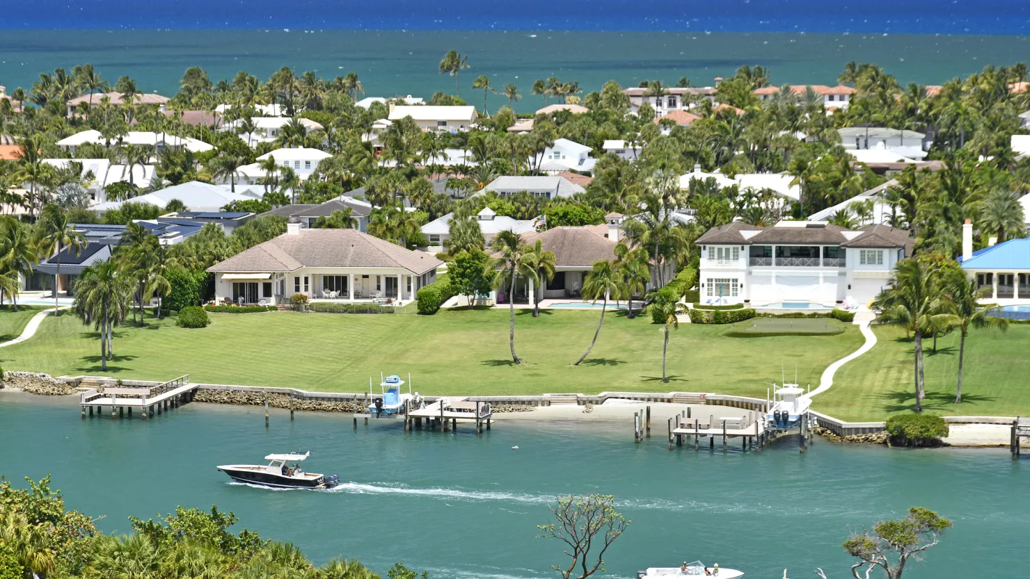 Aerial view of luxury waterfront homes with private docks and lush landscaping in Boca Raton, Florida, showcasing high-end coastal real estate.