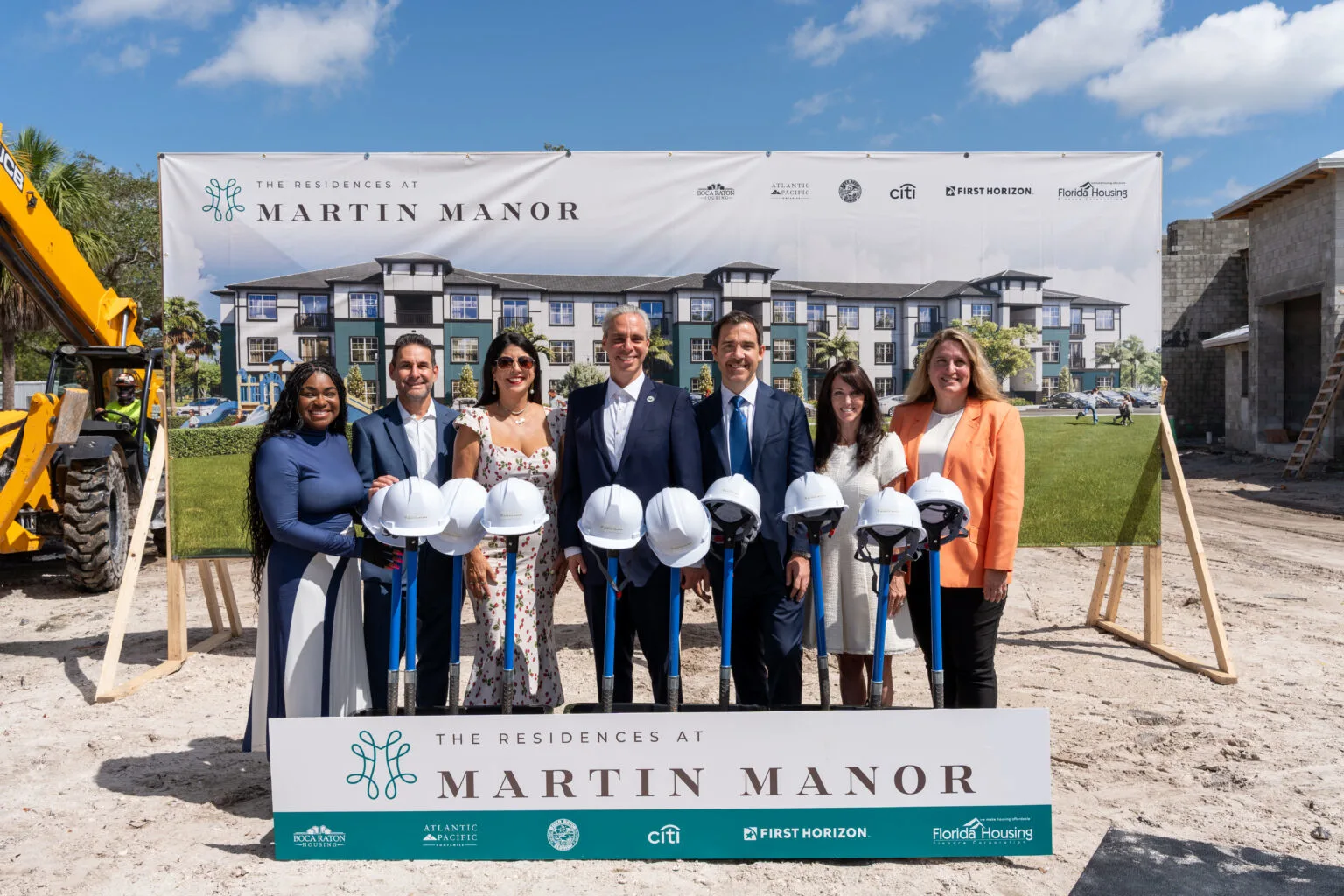 Officials, developers, and community leaders at the groundbreaking ceremony for the Residences at Martin Manor in Boca Raton, standing in front of a project banner and construction site.