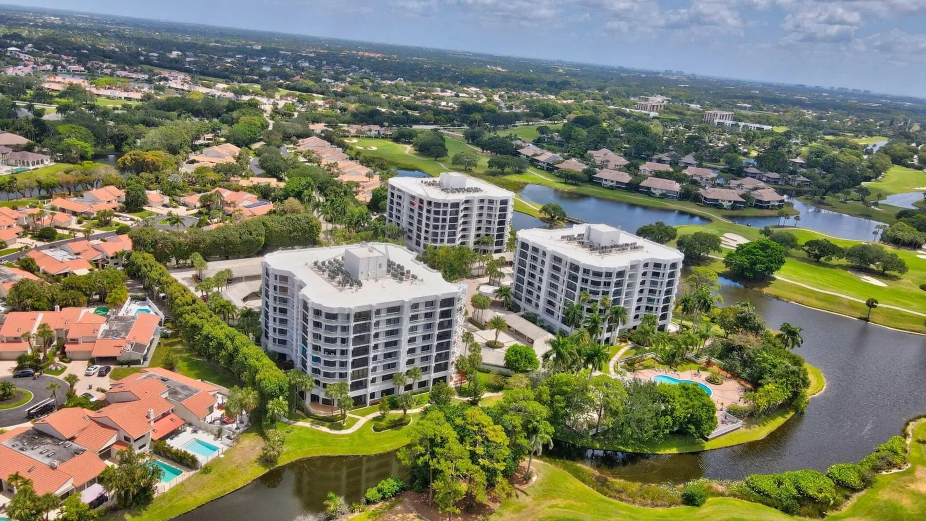 Aerial view of Fairway Point Condos in Boca West Country Club, Boca Raton, featuring three condo buildings surrounded by golf courses, ponds, and greenery.