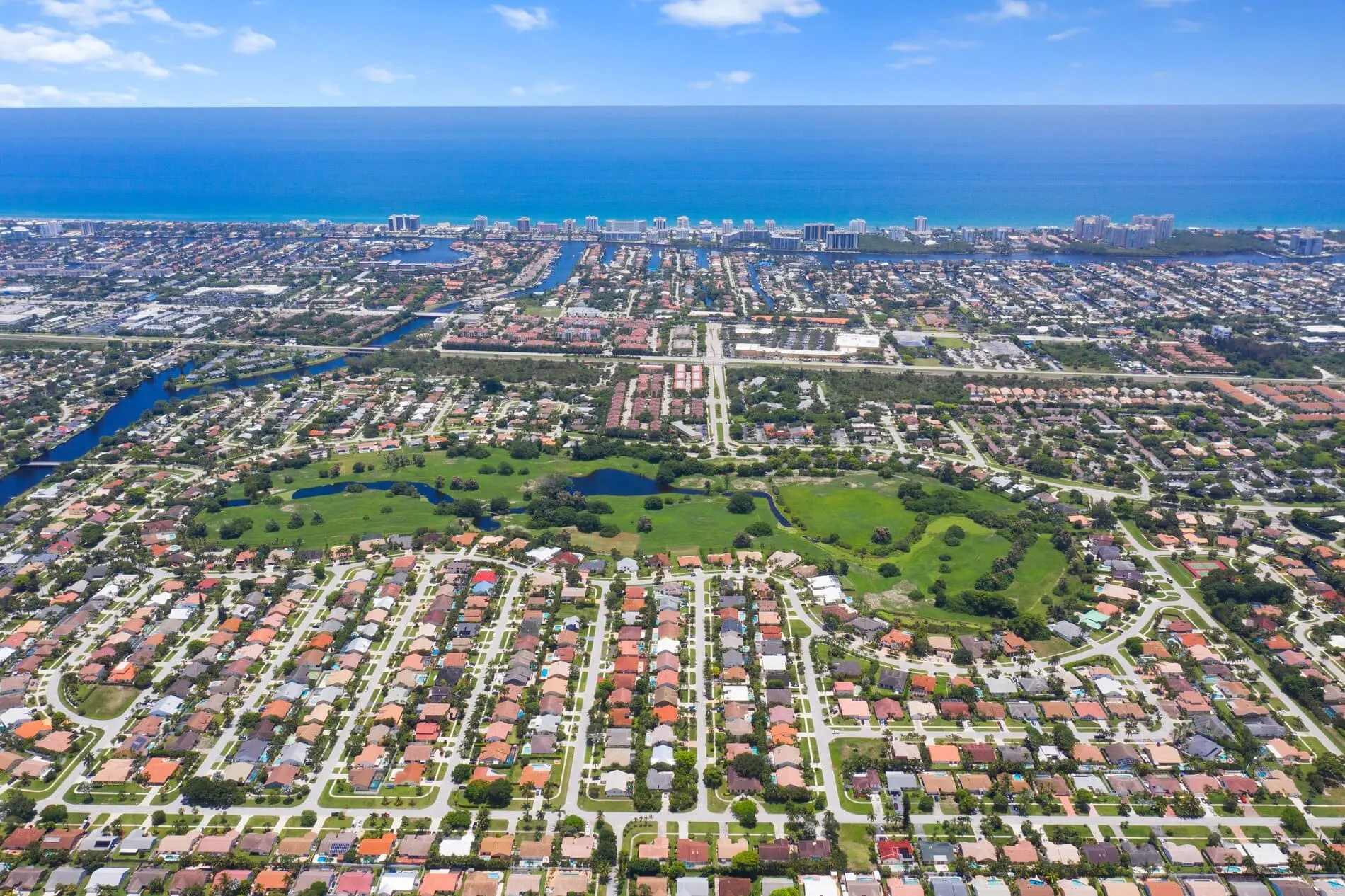 Aerial view of Hidden Valley neighborhood featuring homes, golf course, canals, and coastline in the distance.